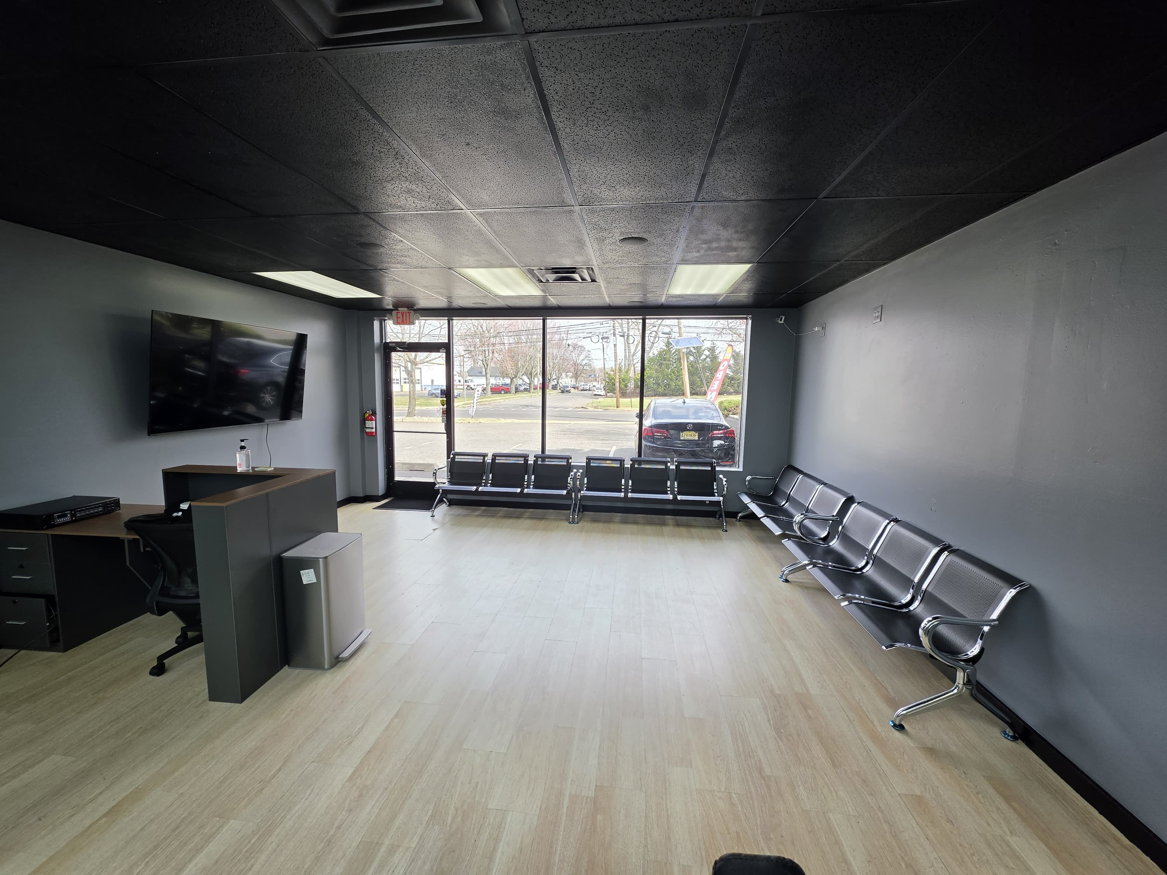 Waiting area at Legacy Studio Barbershop with bench seating, a wall-mounted TV, and the reception desk